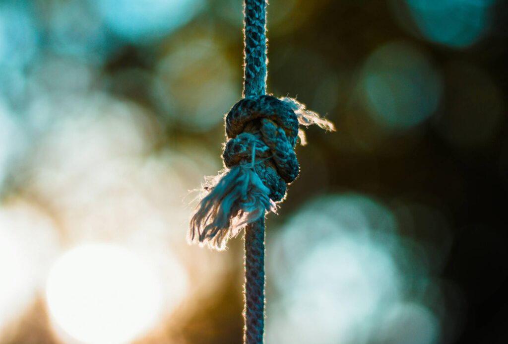A rope with multiple knots tied together, frays are starting at the ends.