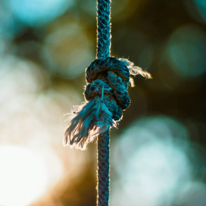 A rope with multiple knots tied together, frays are starting at the ends.