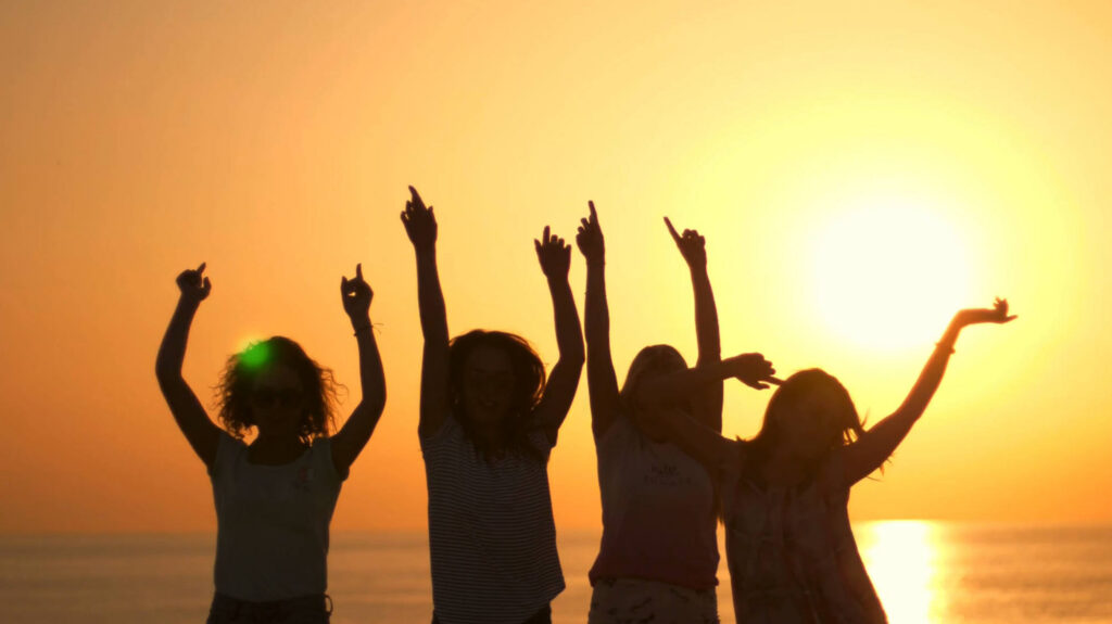 Young people dancing at the beach while the sun sets in the background. From the Mossbeard song - Only so many summers.