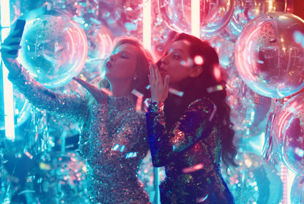 Two young woman at a party taking selfies and recording a live view for social media. From the Mossbeard song - The unseen