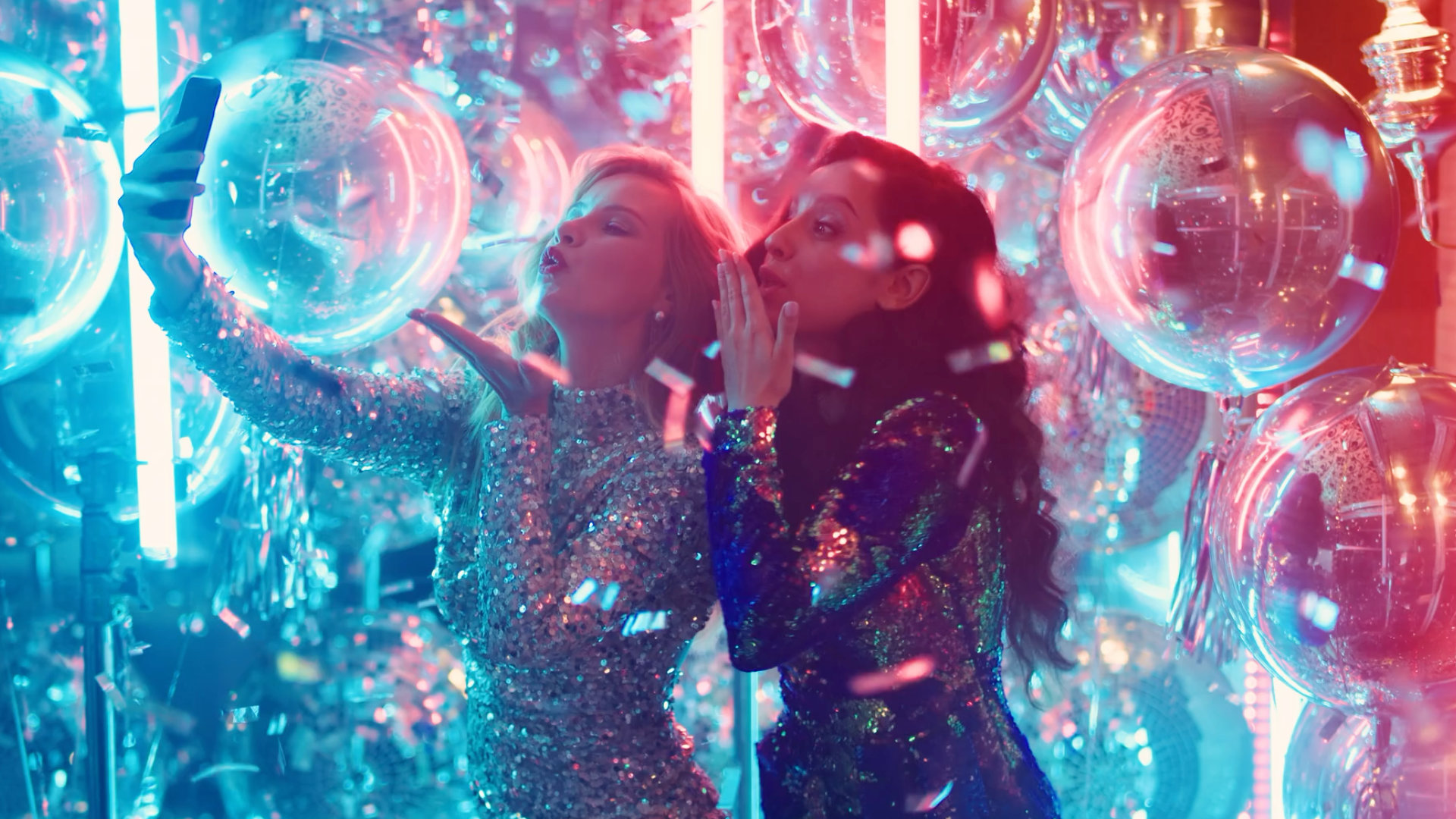 Two young woman at a party taking selfies and recording a live view for social media. From the Mossbeard song - The unseen