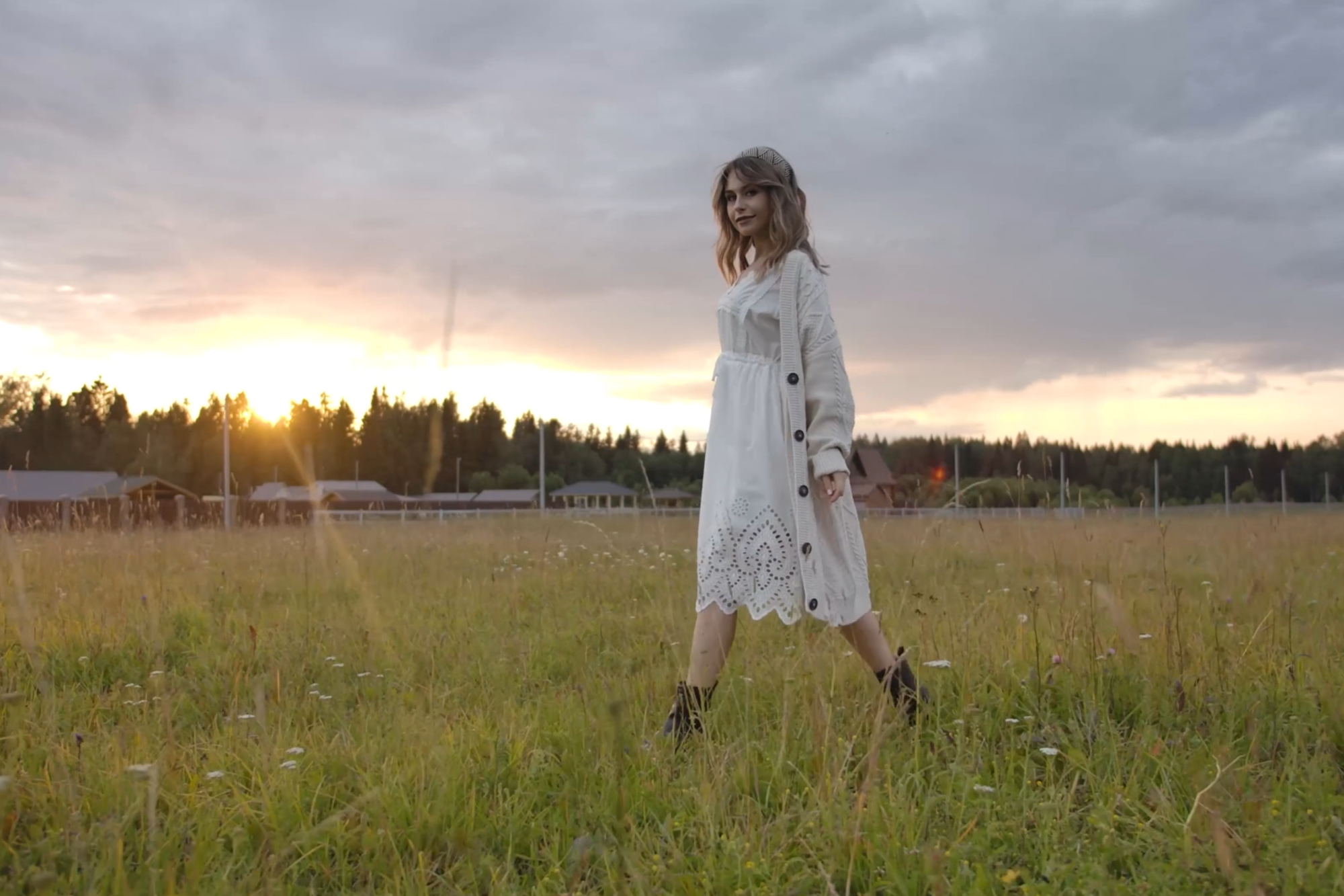 Mossbeard -Favourite mystery - A beautiful young woman wearing a white dress and boots, walks across a country field at sunset.