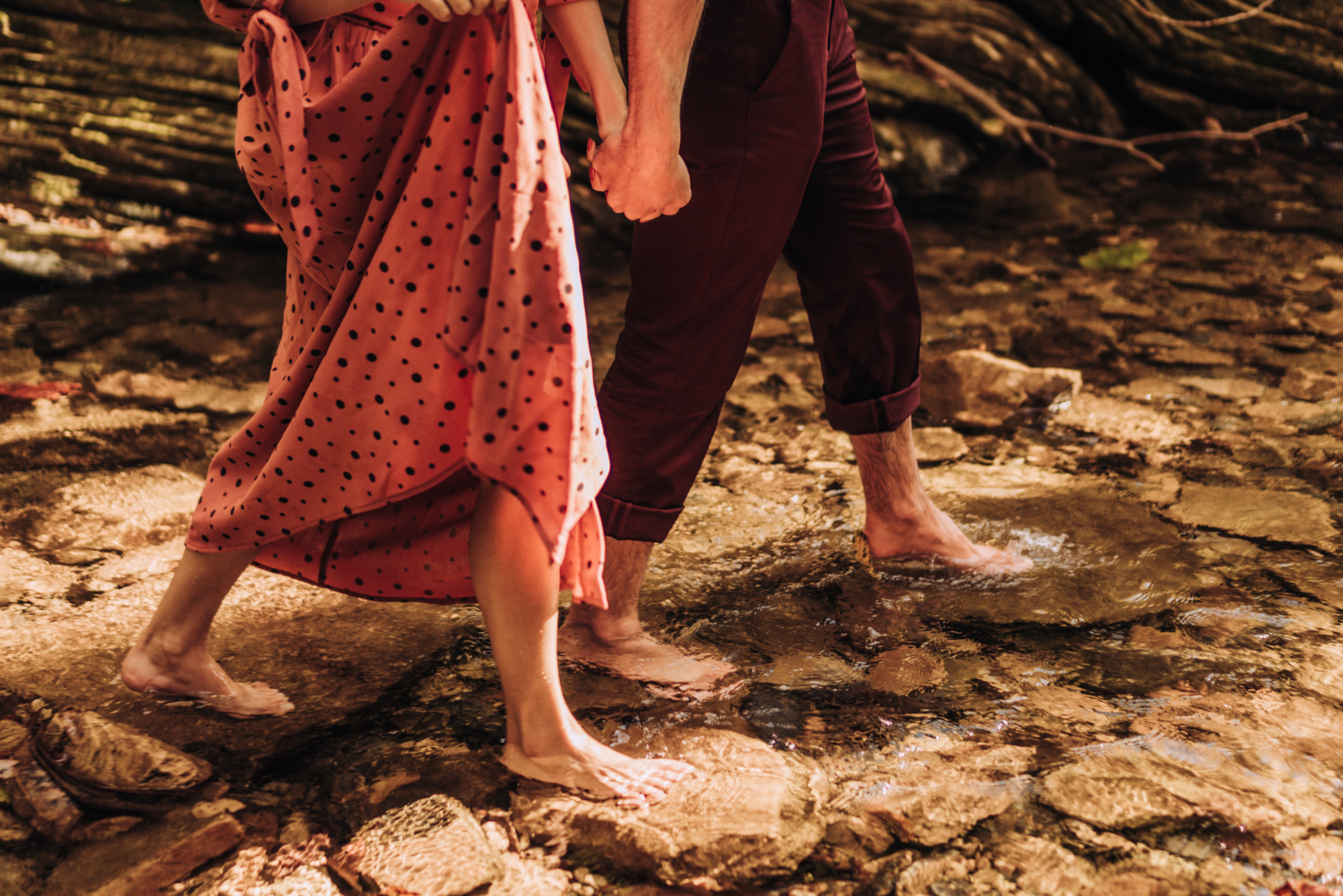 Mossbeard - Pathmaker - A man and a woman hold hands and walk bare footed through a shallow stream.