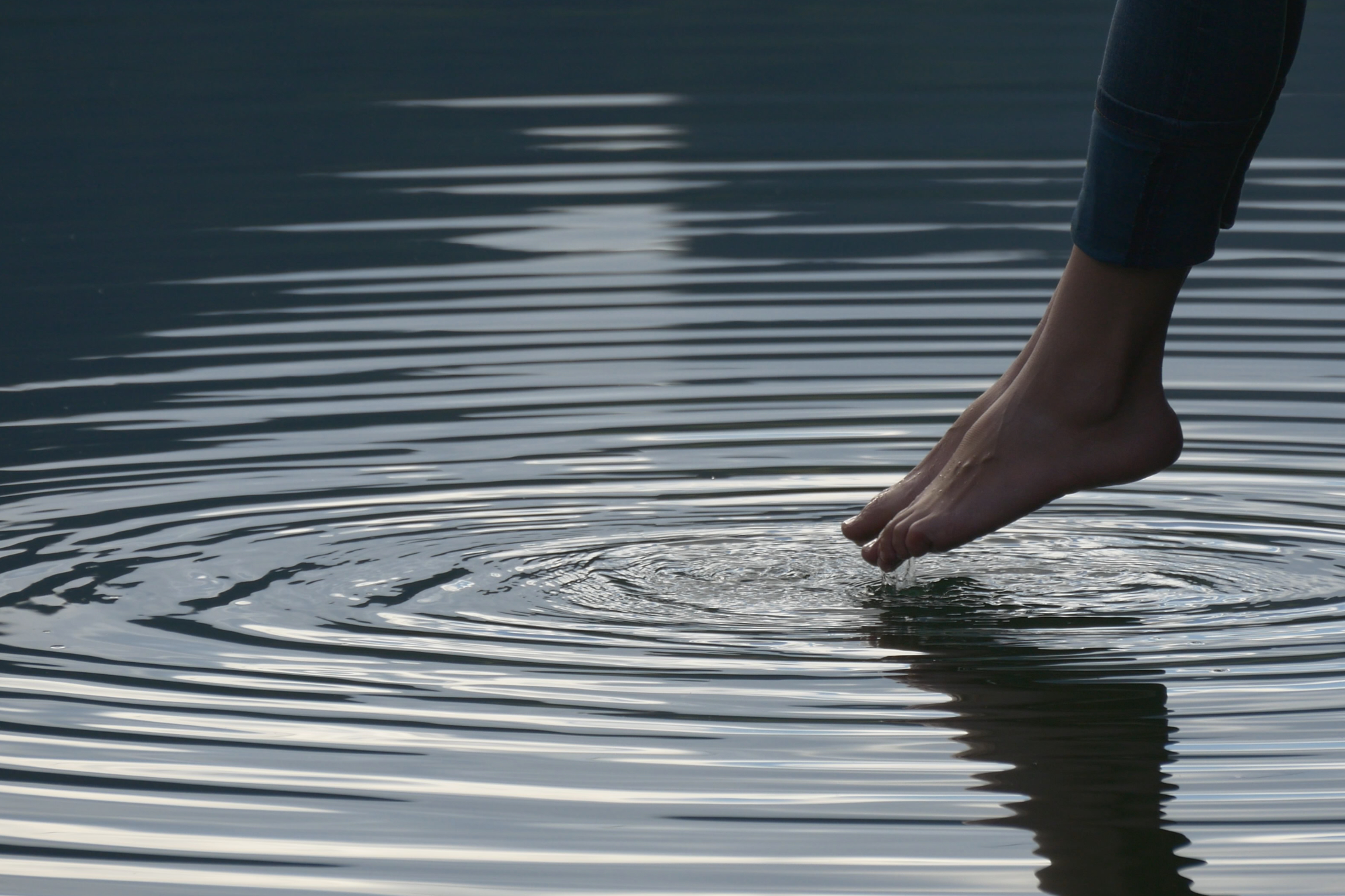 Mossbeard - The ripple - A close up of a woman's feet being dipped into a pond, creating a ripple.